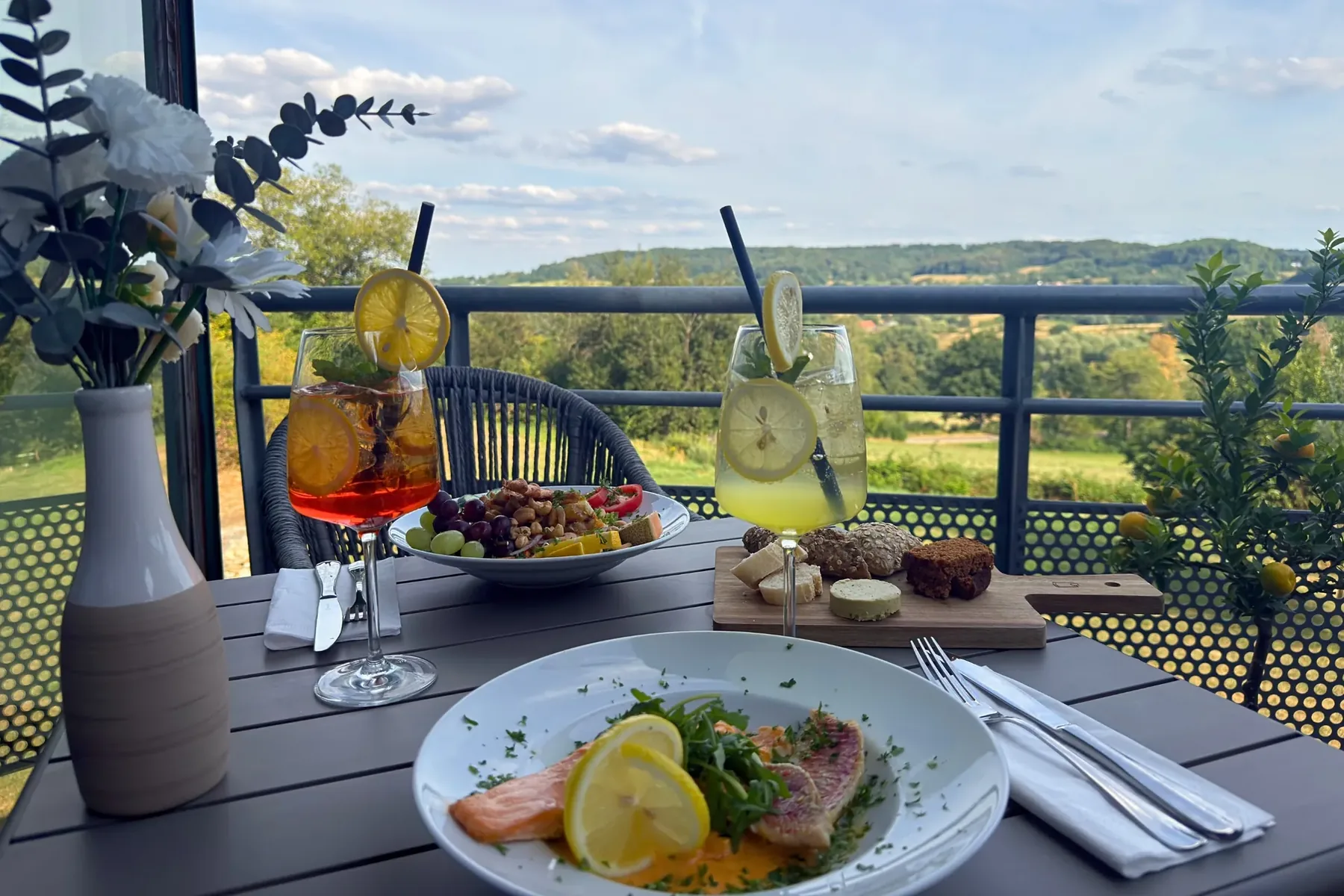 Terrace table with a fish dish, nibbles and cocktails, overlooking the hills