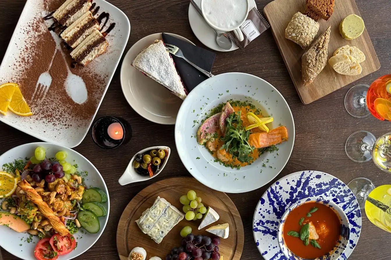 A table full of dishes at Giraffe Lodge, from soup and salad to fish, cheese and tiramisu