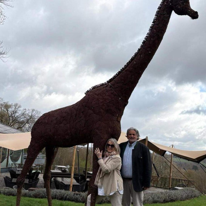 Owners Wolfgang and Ursula by the giraffe sculpture at Giraffe Lodge