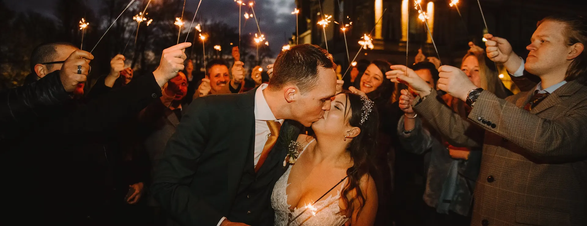 Couple kissing among guests holding sparklers, wedding organised by FBLS Weddings